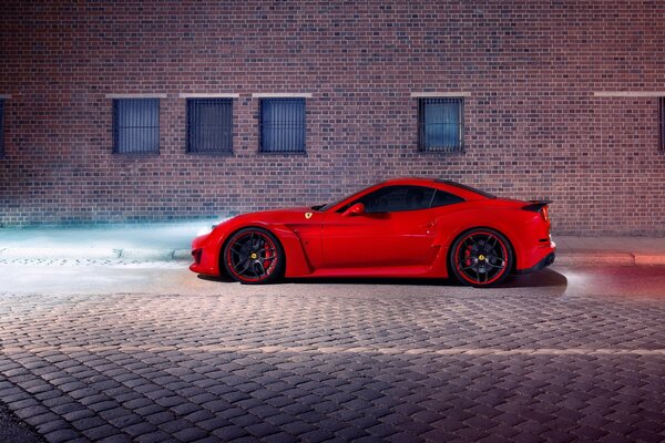 Leuchtend roter Ferrari auf dem Hintergrund einer Backsteinmauer