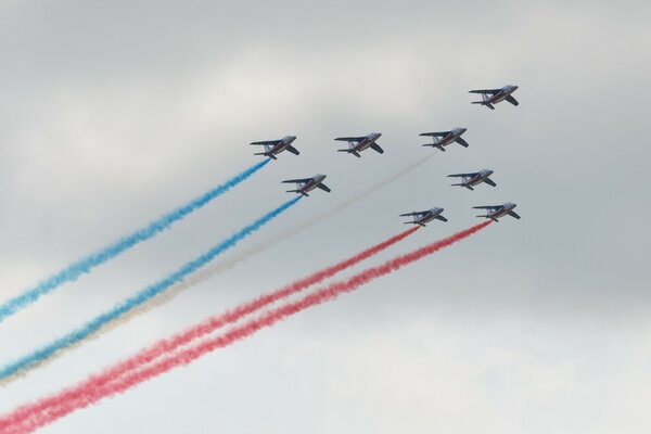 Das Flugzeug am Himmel lässt blau-rot-weißen Rauch frei