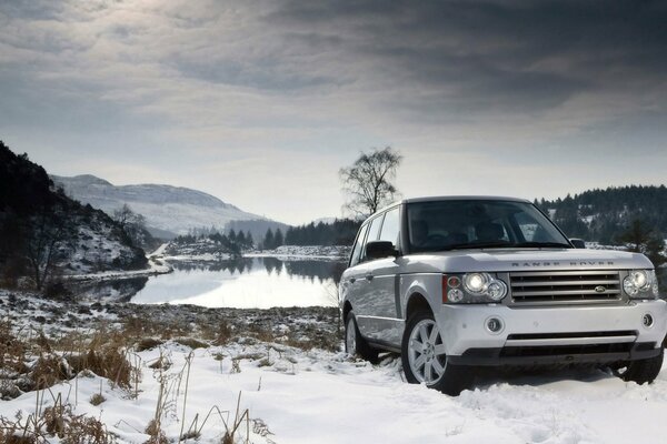Weißer Land Rover in einer Winterlandschaft in der Nähe eines Sees