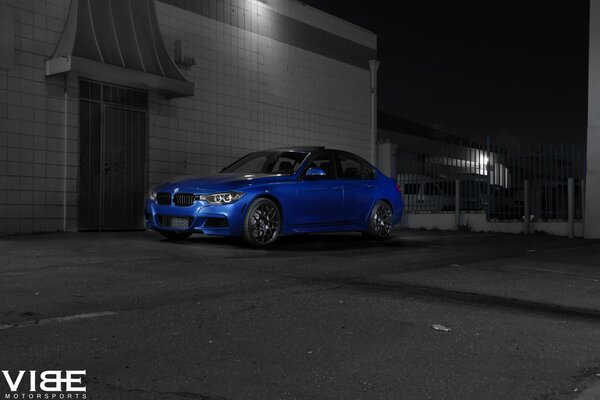 Blue BMV at night on a gray wall background