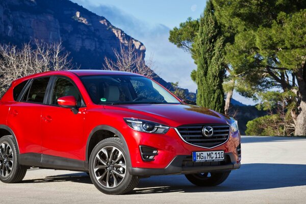 Red Mazda CX-5 crossover on a rock background