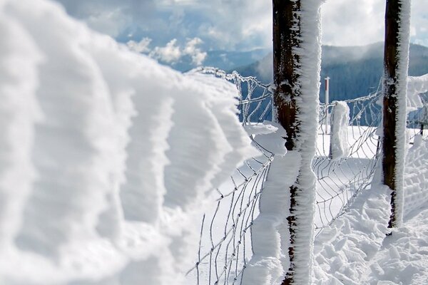 Valla de nieve en el fondo de las montañas de invierno