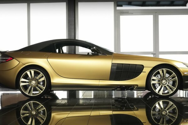 Golden mansory mercedes-benz on the background of panoramic windows. Luxury car in gold color