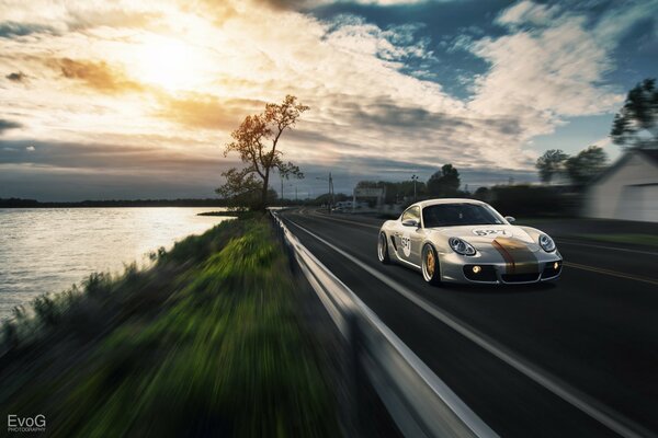 Porshe au coucher du soleil, se précipite sur la piste le long de la mer