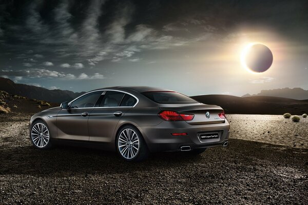 Grey matte BMW on the background of a solar eclipse