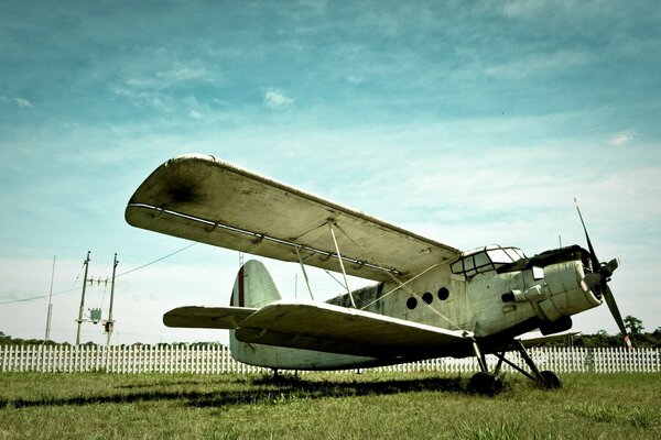 The plane is fenced with a fence grass is under it and the sky is above