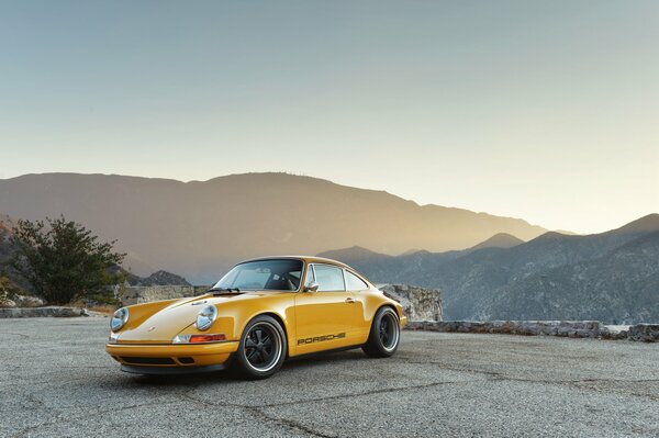 Gelber Porsche auf dem Hintergrund der schönen Berge