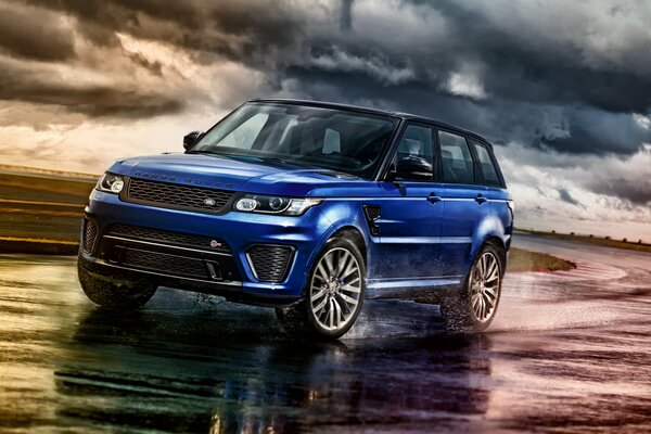 Blue range rover rides on a wet road