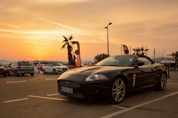 Sports car in the parking lot on the background of sunset
