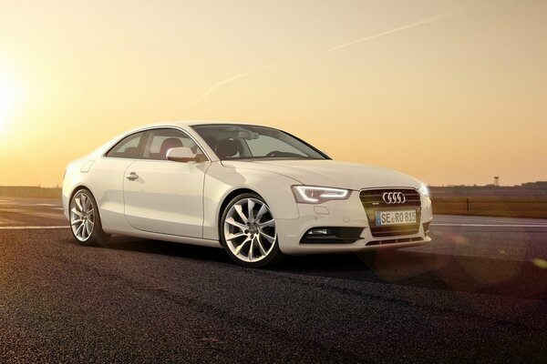White Audi in the rays of the setting sun