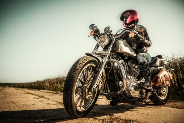 A girl in a motorcycle helmet on a bike on a grass background