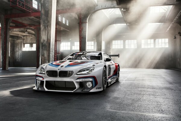 A white sports car in a hangar filled with the sun