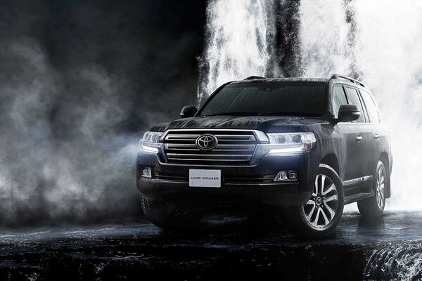 Toyota Land Cruiser noir près d une cascade dans la brume