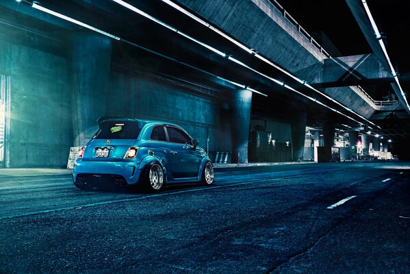 Azul mate Fiat Abarth f132 contra las carreteras grises de la ciudad