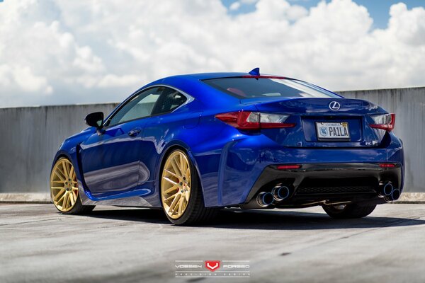 Bright blue lexus with gold wheels on a background of clouds