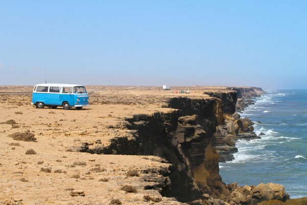 Minibus at the foot of the mountain on the background of the sea with waves