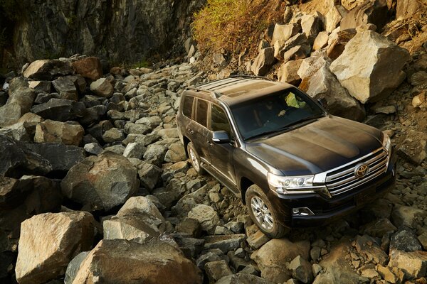 Toyota Land Cruiser sullo sfondo di una strada rocciosa e montagne