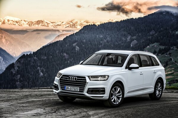 Audi q7 blanco en el fondo de una montaña boscosa