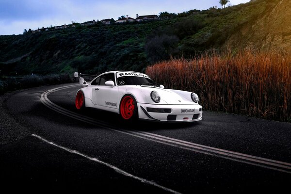 Un coche de carreras blanco monta en el camino a lo largo de las montañas