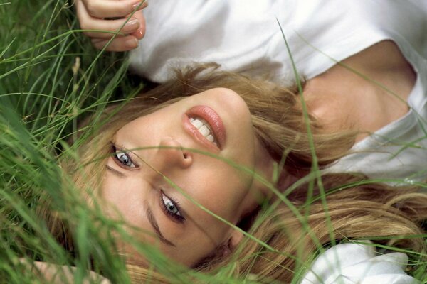 Blondes Mädchen lächelt sexuell im Gras liegend