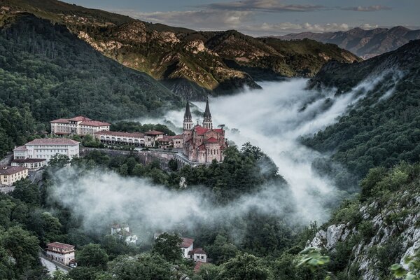 Un enorme castillo se eleva sobre los árboles en las montañas