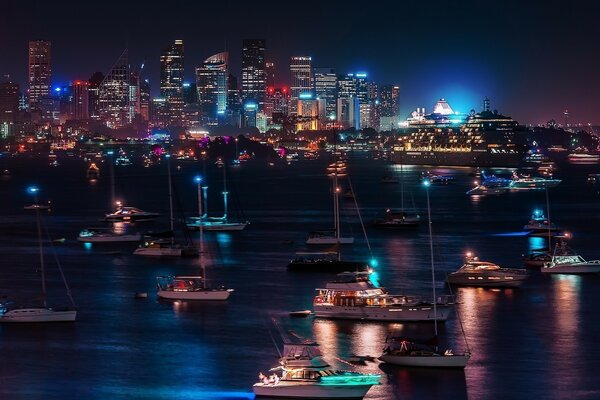 Vista de la ciudad nocturna desde la orilla del río, que tiene muchos yates