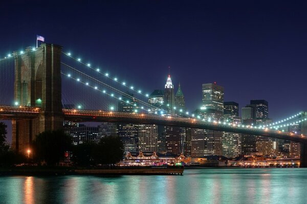 The river is illuminated by the light from the bridge of the night city