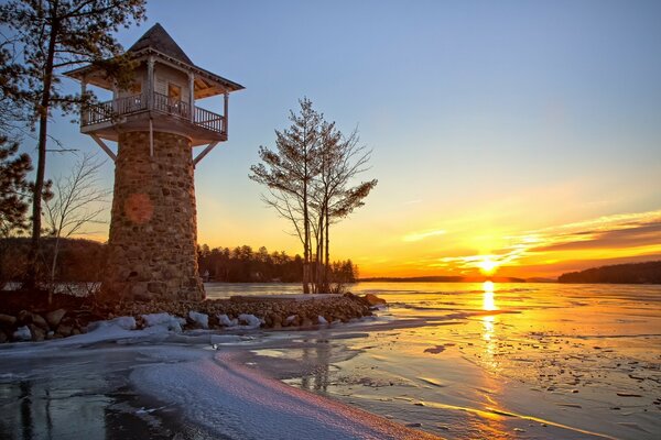 Paisaje con un faro en el fondo de la puesta de sol