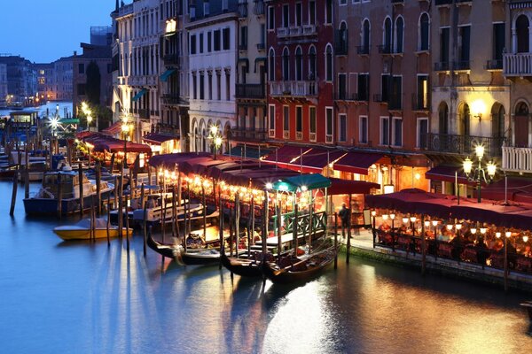 Gondole sul molo di Venezia. Italia notturna, canale illuminato da lanterne