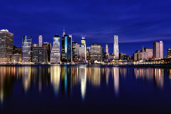 Die Wolkenkratzer des abendlichen New Yorks spiegeln sich im Wasser wider