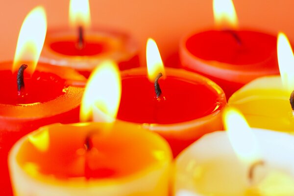 Цветные, заженные свечи на оранжевом фоне