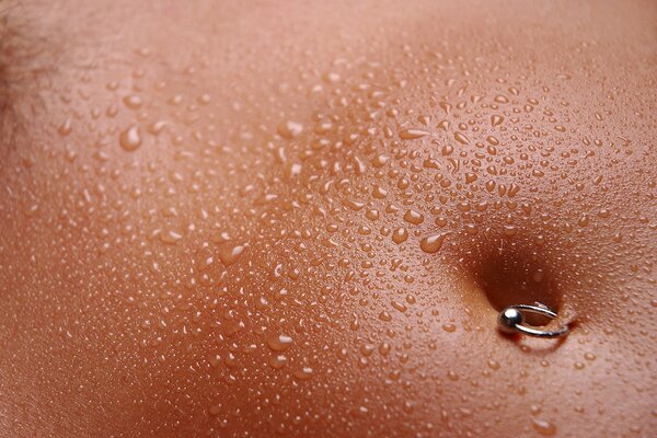 Belly with water drops and an earring on the navel