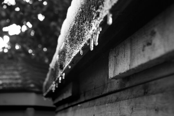 Eiszapfen hängen von einem Holzhaus