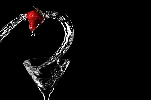 Transparent splash of water from a glass with strawberries on a black background