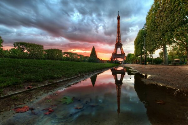 The Eiffel Tower is reflected in a puddle