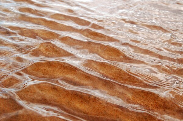 Sand through the ripples of sea waves