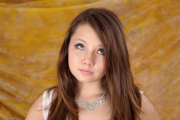 Thoughtful brown-haired woman with delicate makeup in a necklace with rhinestones