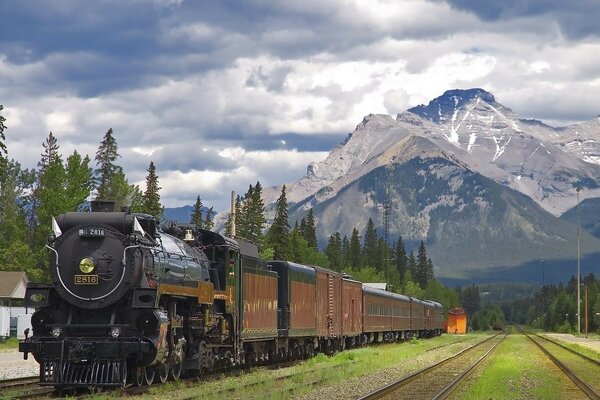 Locomotive à vapeur à la station dans les montagnes sur un ciel nuageux