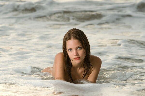 Ragazza con i capelli bagnati in posa in schiuma di mare