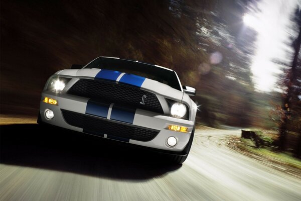 White car with two blue stripes at high speed