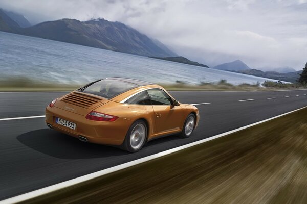 Voiture orange sur fond de montagnes et de la mer