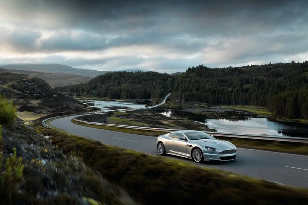 Aston-Martin plateado corriendo por la carretera