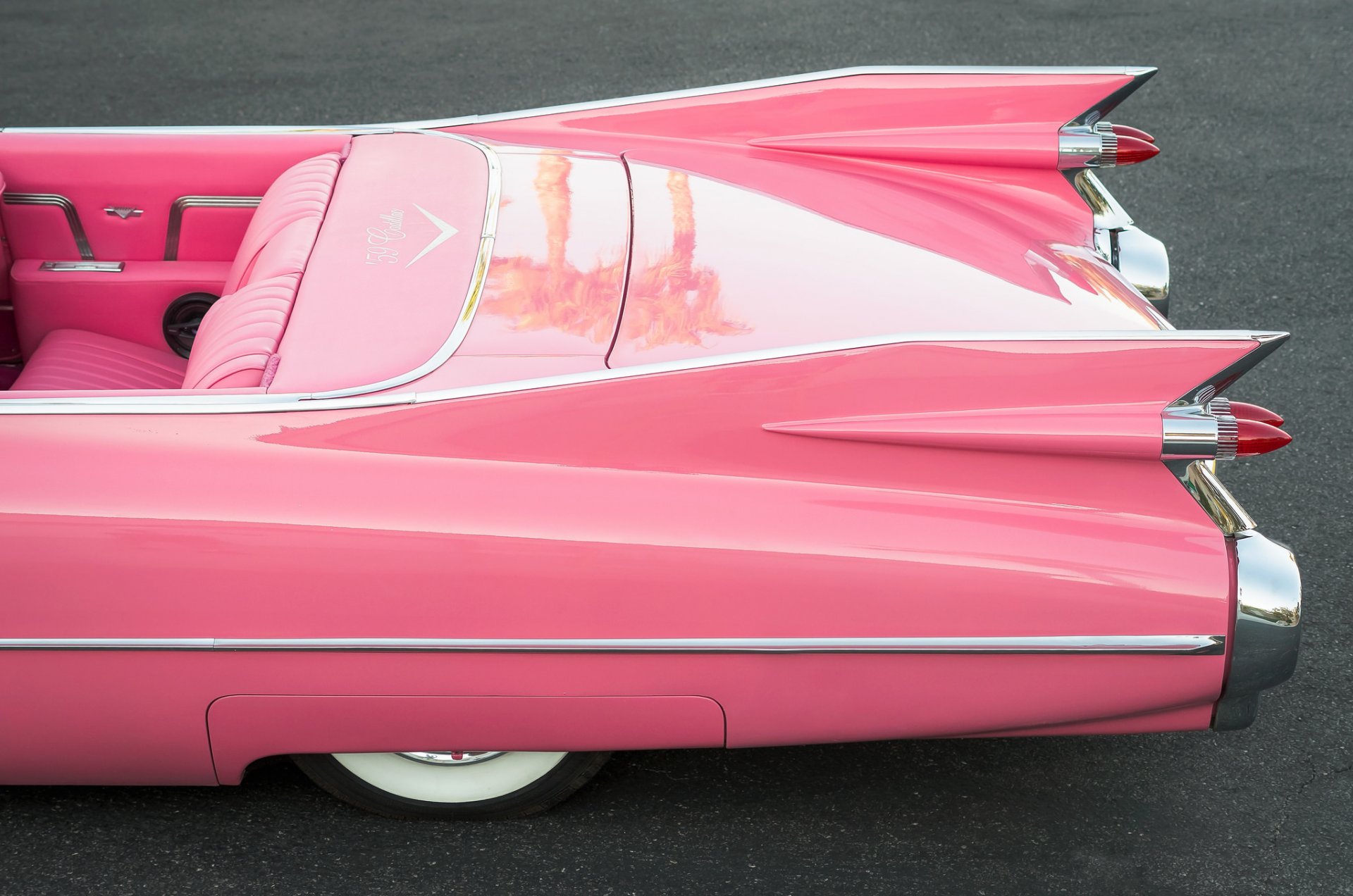 Side view of a pink convertible on the road.