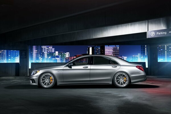 Beautiful profile of a gray car in front of a night city