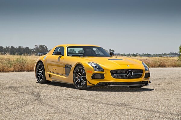 Une Mercedes jaune se tient sur un terrain strié de roues