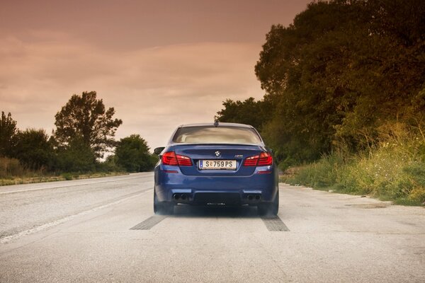 Blue bmw on the road with sky clouds