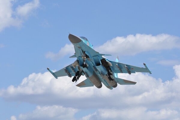 A flying Su-34 plane in blue clouds