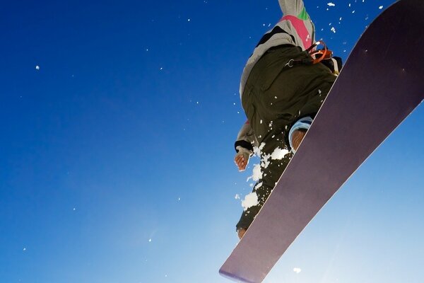 Bezchmurne błękitne niebo z snowboardzistą zbliżenie