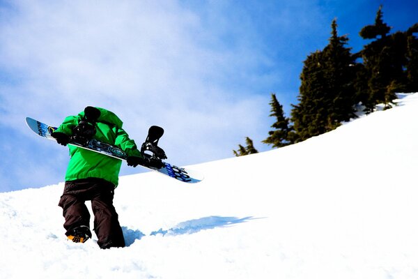 A snowboarder walks through snowdrifts