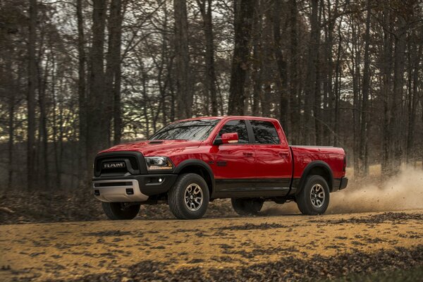 The maroon car is standing in the forest among the trees